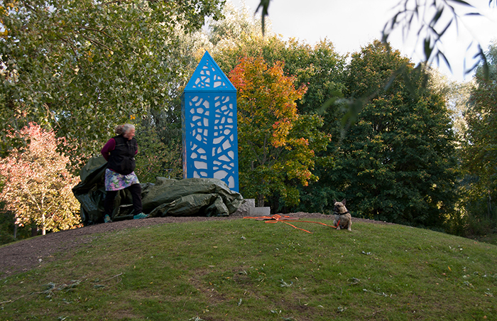 Konstnär med hund avtäcker en skulptur